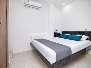 a bedroom with a large white bed with blue pillows at Hotel Masinda in Cartagena de Indias