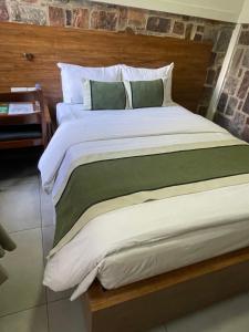 a large bed with white sheets and green pillows at KIGALI FANTASTIC Aparthotel in Kigali