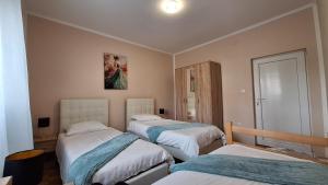 a bedroom with three beds and a painting on the wall at Veslo IN in Krčedin