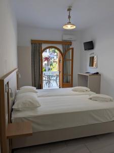 a bedroom with a large white bed and a balcony at Two Brothers Parga in Parga +6 photos