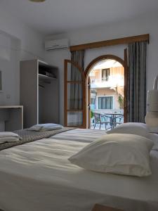 a bedroom with a large white bed and a balcony at Two Brothers Parga in Parga