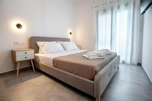 a bedroom with a large bed with a nightstand and a window at Sea U - Apartment in Skala Marion
