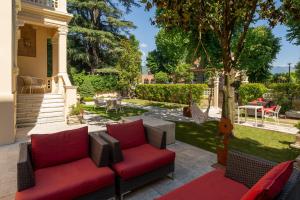 a patio with red furniture and a tree at UNAHOTELS Villa dei Platani Foligno in Foligno