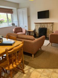 a living room with couches and a fire place at Westlea Cottage in Turriff