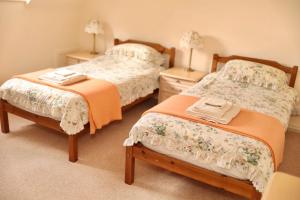 a bedroom with two beds and two night stands at Westlea Cottage in Turriff