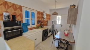 a small kitchen with a microwave and a table with a tableablish at Menzel Rayan in Midoun