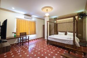 a bedroom with a bed and a desk and a television at Krish Inn in Chidambaram