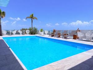 a swimming pool with chairs and the ocean in the background at CALIXTA Hotel in Playa del Carmen