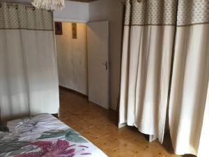 a bedroom with curtains and a bed and a door at Maison des barrys in Ispagnac