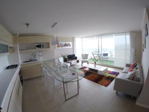 cocina y sala de estar con mesa de cristal en Departamento Vista al Mar, Laguna Bahia, Algarrobo 1205H, en Algarrobo