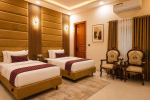 a hotel room with two beds and a chair at City Rooms in Karachi