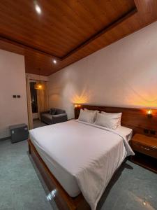 a bedroom with a large white bed and a couch at Juna Guest House in Uluwatu