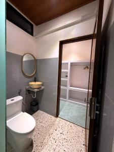a bathroom with a toilet and a sink and a mirror at Juna Guest House in Uluwatu +46 photos