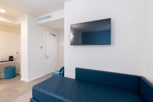 a living room with a blue couch and a flat screen tv at Acciuga Hotel in Laigueglia