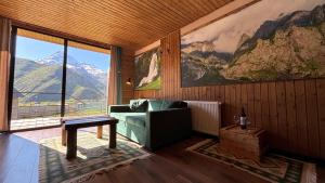 a living room with a couch and a large window at Mtaura Cabins in Kazbegi