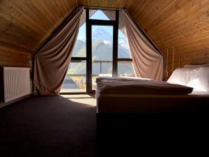 a bedroom with a bed and a large window at Mtaura Cabins in Kazbegi