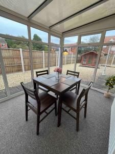 a dining room with a table and chairs and windows at Park Cottage in Scunthorpe