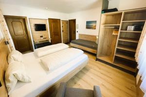 a bedroom with a large white bed and wooden floors at Pension Glockenstuhl in Finkenberg