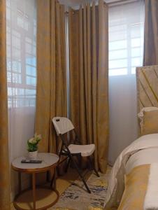 a bedroom with a chair and a table and a bed at Bliss Apartments in Nakuru