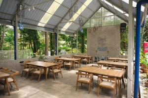 a restaurant with wooden tables and chairs and windows at HeHa Waterfall Suites & Camping Ground in Paragajen