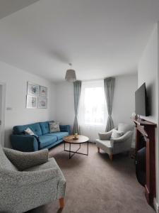 a living room with a blue couch and chairs at Sand Castle in Weymouth
