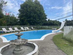 a swimming pool with a fountain and chairs around it at Motel Le Voyageur in Saint-Jérôme