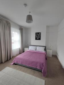 a bedroom with a bed with a purple blanket at Sand Castle in Weymouth +29 photos