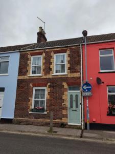 a brick house with a blue door on a street at Sand Castle in Weymouth
