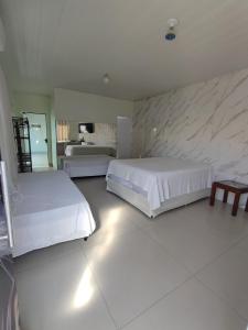 a bedroom with two beds and a stone wall at Quarto Califórnia in Campo Novo do Parecis