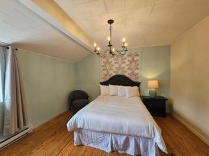 a bedroom with a bed and a chandelier at Auberge Lever L'Ancre in Sainte-Hélène-de-Kamouraska