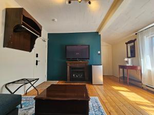 a living room with a flat screen tv and a fireplace at Auberge Lever L'Ancre in Sainte-Hélène-de-Kamouraska