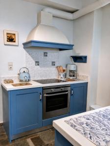 a kitchen with blue cabinets and a stove top oven at Stellinas House 2 in Andros