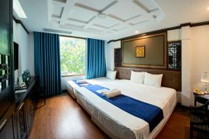 a bedroom with a large bed with blue curtains at Ha Noi Capital Boutique Hotel in Hanoi