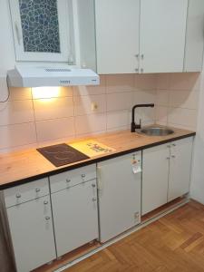 a kitchen with white cabinets and a sink at Apartman studio DUE Apatin in Apatin