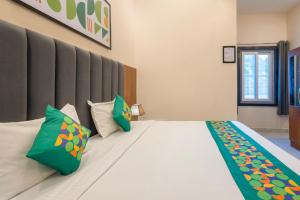 a bedroom with a large bed with green pillows at Treebo Ayodhya Grand in Madnāpur +22 photos