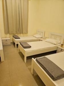 a room with three beds and a window at Iman Guest House in Al Qurayyah