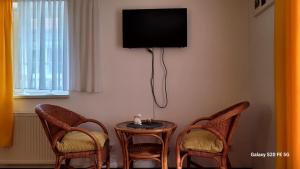 a room with two chairs and a table with a tv on the wall at Pension Yammas in Großpostwitz