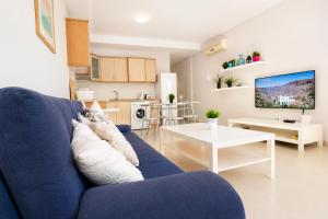 a living room with a blue couch and a kitchen at OPEN SKY VALLEY in Mogán