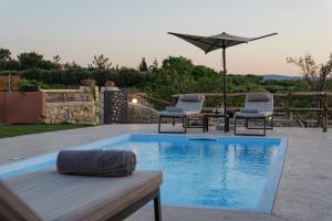 a swimming pool with two chairs and an umbrella at Stavlos Villa - Private Pool in episkopi-heraklion