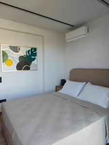 a bedroom with a bed and a painting on the wall at Aura Mare in Porto Rafti +49 photos
