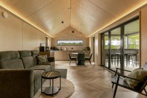 a living room with a couch and a table at Lėtai resort, Lakefront Nature Stay with Sauna in Eželiškės