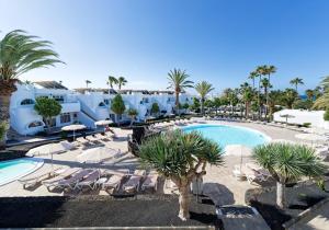 a resort with a pool and chairs and palm trees at Hotel Floresta in Puerto del Carmen