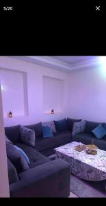 a living room with a blue couch and a table at jardin de raisin in Bouznika