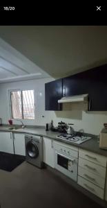 a kitchen with a stove and a washing machine at jardin de raisin in Bouznika