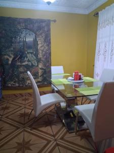 a dining room with a table and chairs and a painting at Alexander b&b in Alajuela