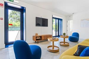 a living room with a yellow couch and blue chairs at Salt&Flow in Parede