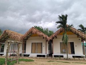 a house with a thatched roof and a palm tree at Ananda Uthaan in Sreemangal