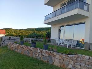 a house with a stone retaining wall and a patio at Villa Twins Dojran in Nov Dojran