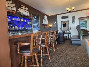 a bar with a row of wooden chairs and a counter at Manoir sur Mer in Sainte-Anne-des-Monts