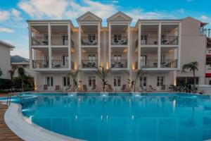 a hotel with a large swimming pool in front of a building at Royal Nidri Suites in Nydri